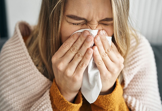 woman with cold blowing her nose 