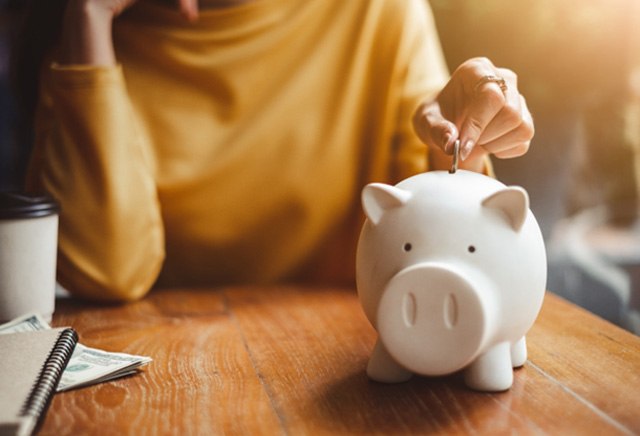 woman putting coin into piggy bank 