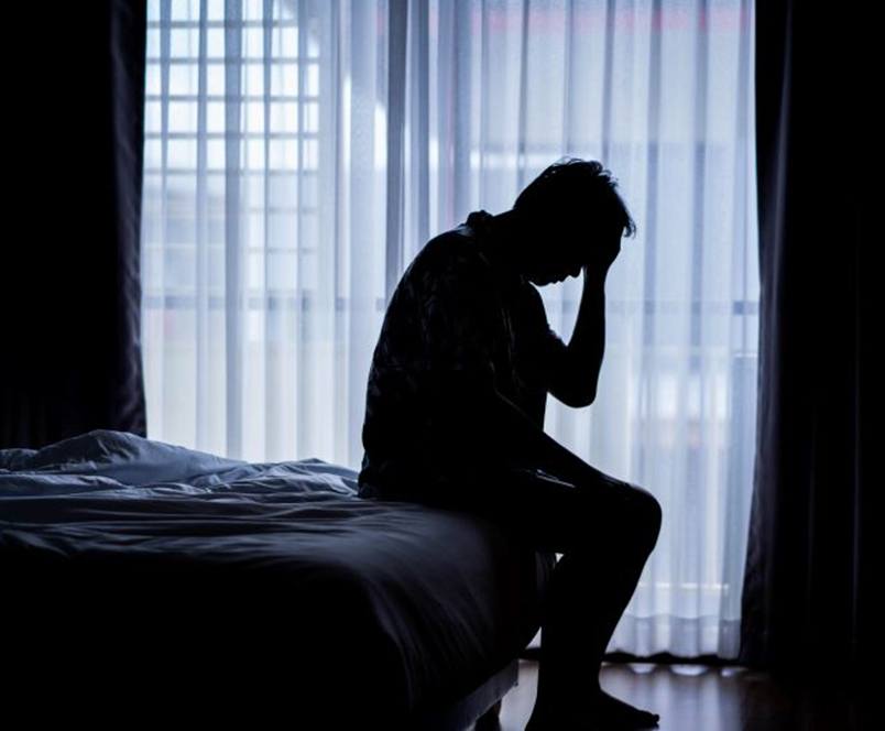 Silhouette of tired man sitting up in bed