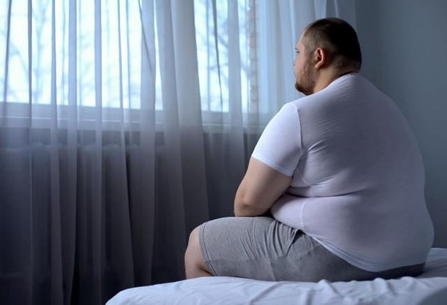 Obese man sitting up in bed