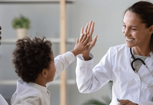 a doctor high-fiving a child patient after lip/tongue-tie treatment