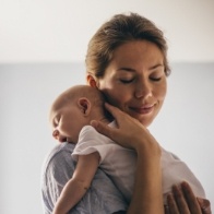 Mother holding sleeping baby after lip and tongue tie release