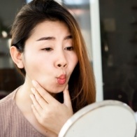 Woman looking at face in mirror after myofunctional therapy