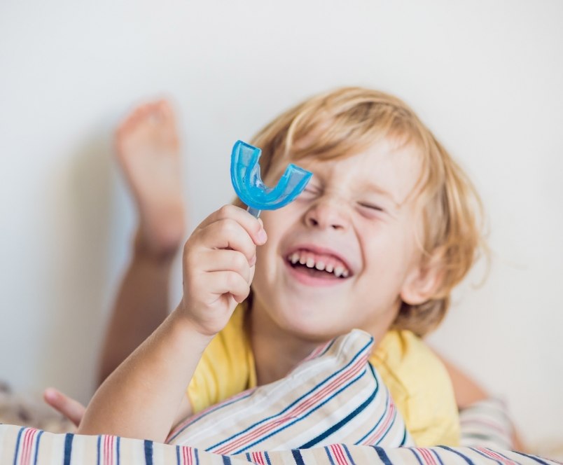 Smiling child holding myofunctional therapy oral appliance