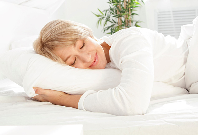 Woman with white shirt sleeping soundly in her bed