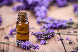 Lavender essential oil next to lavender flowers