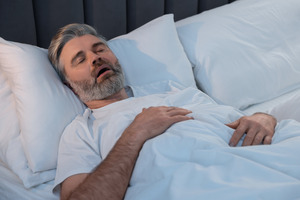 Bearded man with sleep apnea snoring in bed