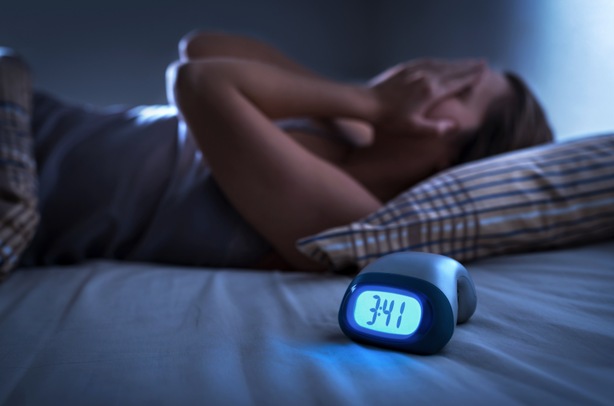 Woman lying in bed with face in hands