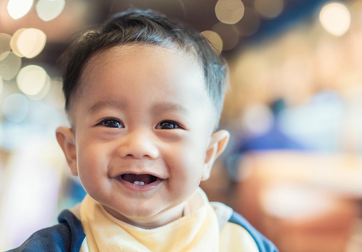 Close-up of a smiling baby with two front teeth showing